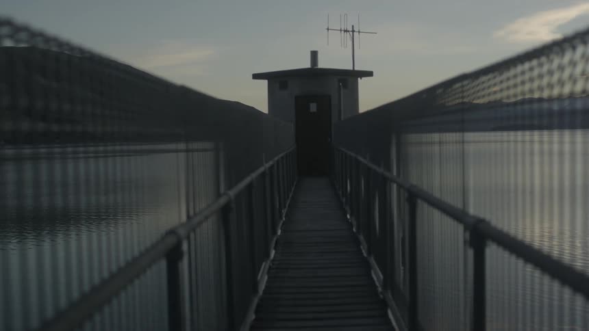 A bridge spans to a small building on the water