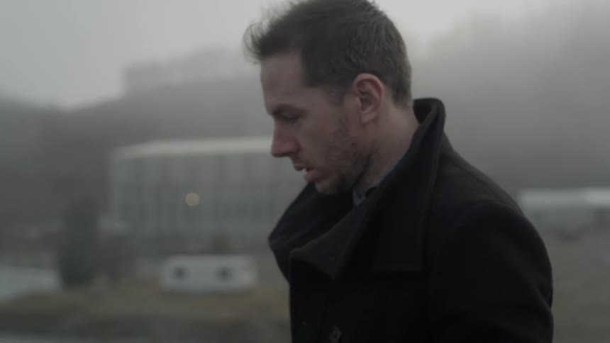A man walking past some buildings on a foggy day
