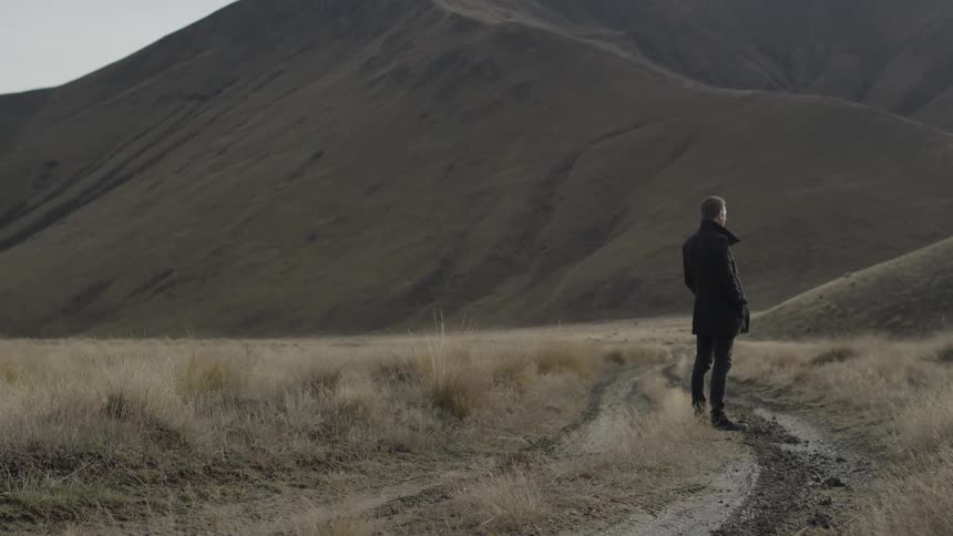 A person standing by a hill