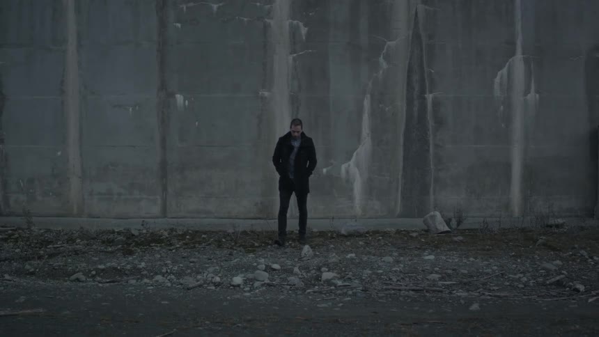 A man walking away from a concrete wall