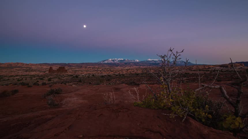 A desert with a colorful sky going from light to dark