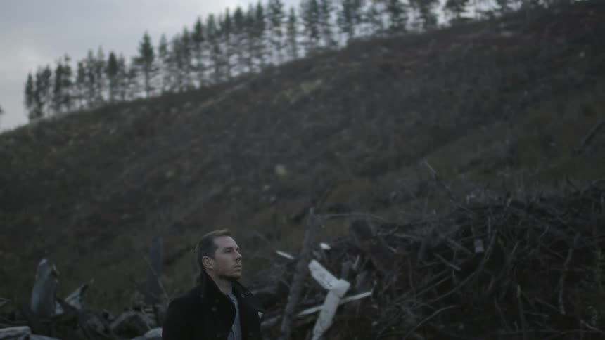 A person standing next to a pile of sticks