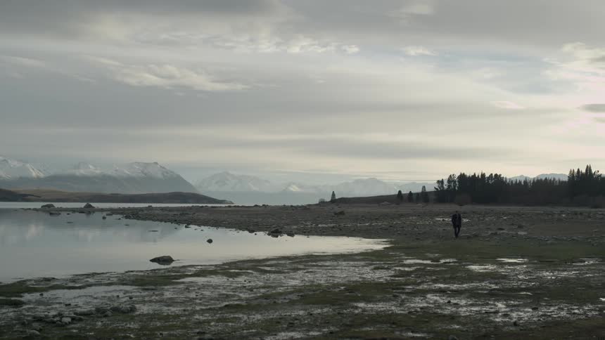 A person walking past a lake