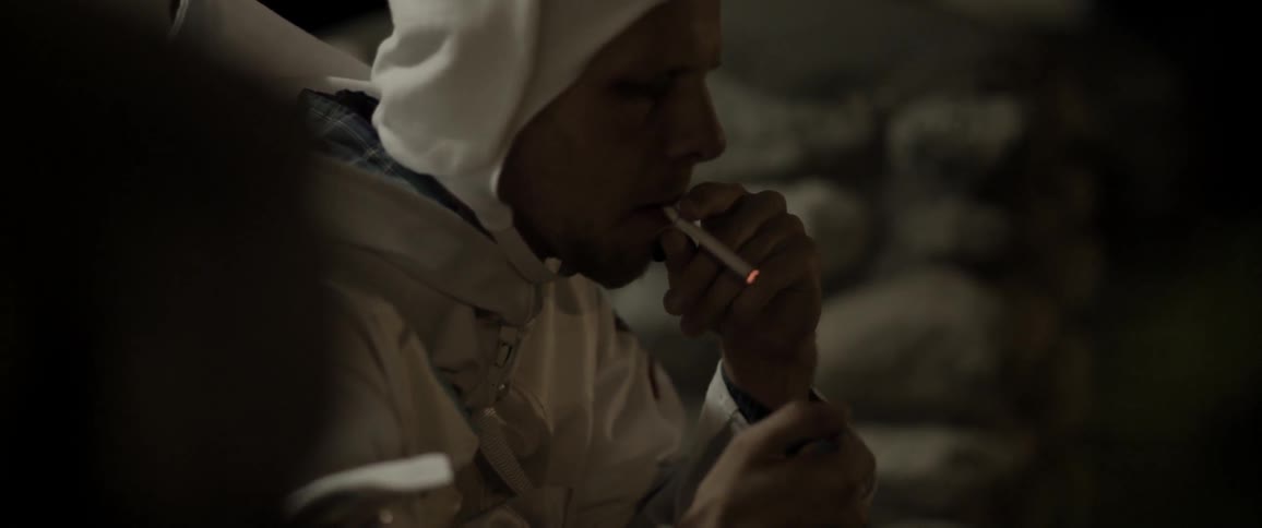 A person in a bulky white suit lighting up a cigarette