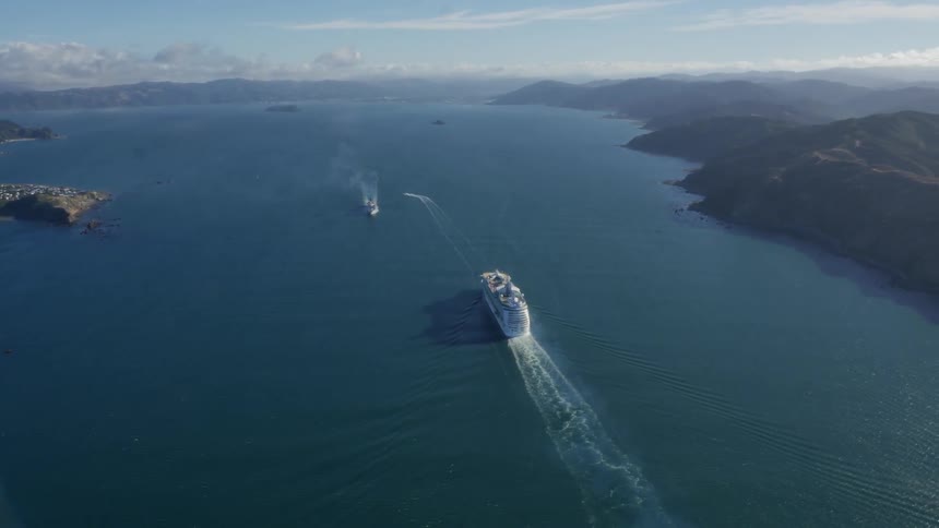 A large ship passes a smaller boat on a clear day
