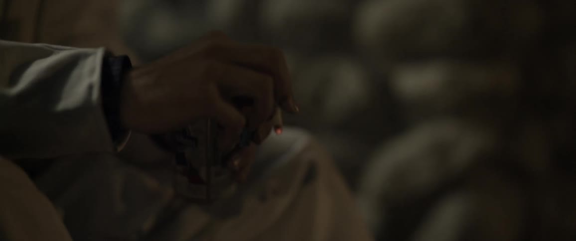 A close-up view of a hand flicking a cigarette, holding a lighter and holding a can of beer