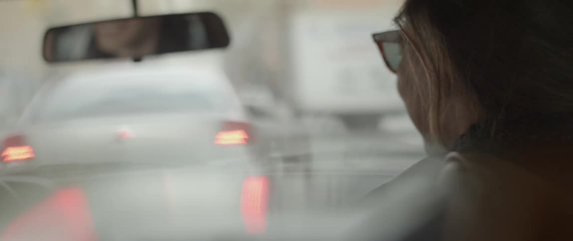 A man and woman kissing and laughing in a car that is stopped in traffic