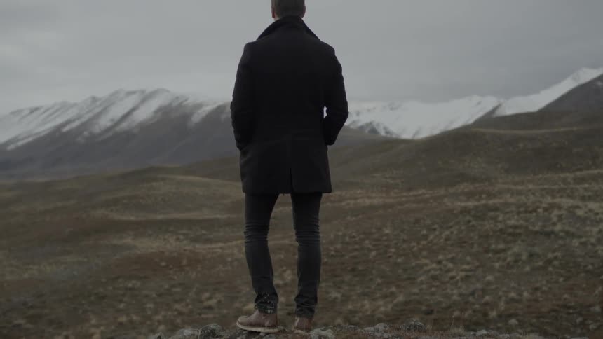 A person standing looking at a mountain