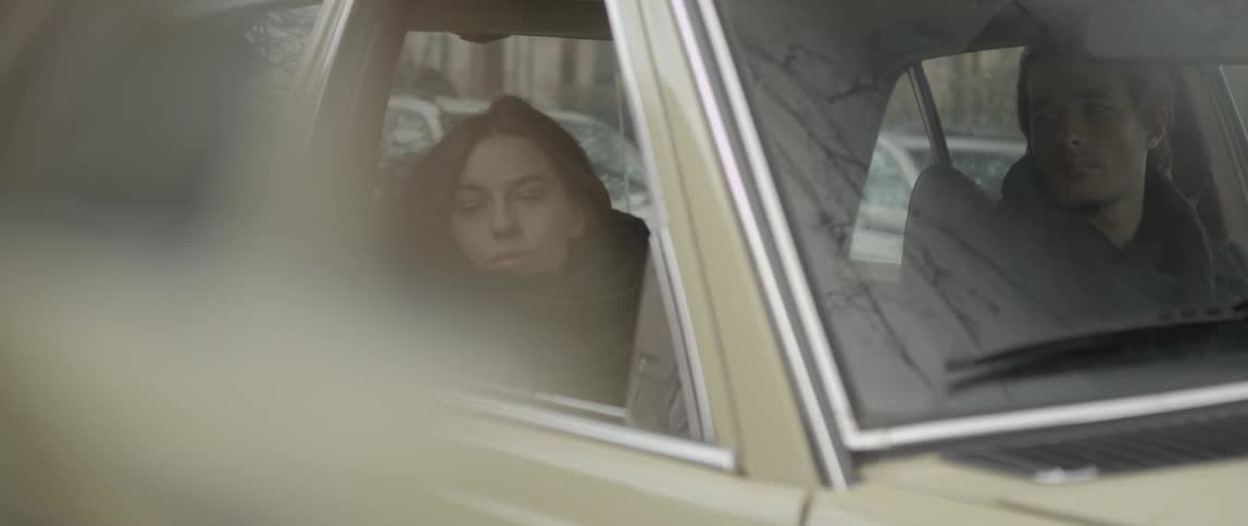 A man and woman sitting in a car on a cold day