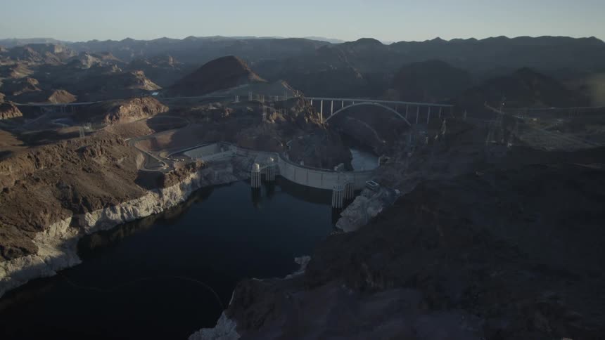 An aerial view of a dam, river and bridge located in the mountains