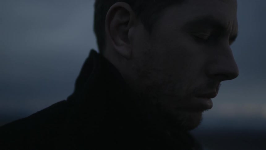 A man looking downwards with furrowed brows