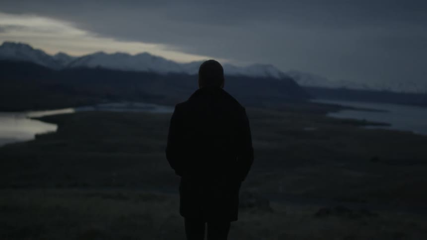 Man stands looking at mountains during evening