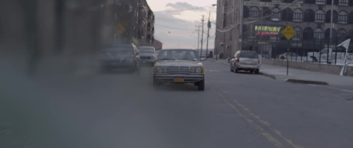 A brown car driving down the street