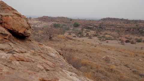View of hills with bushes and dirt on a cloudy day