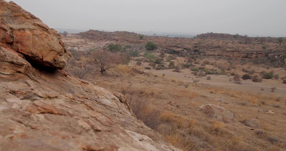 View of hills with bushes and dirt on a cloudy day