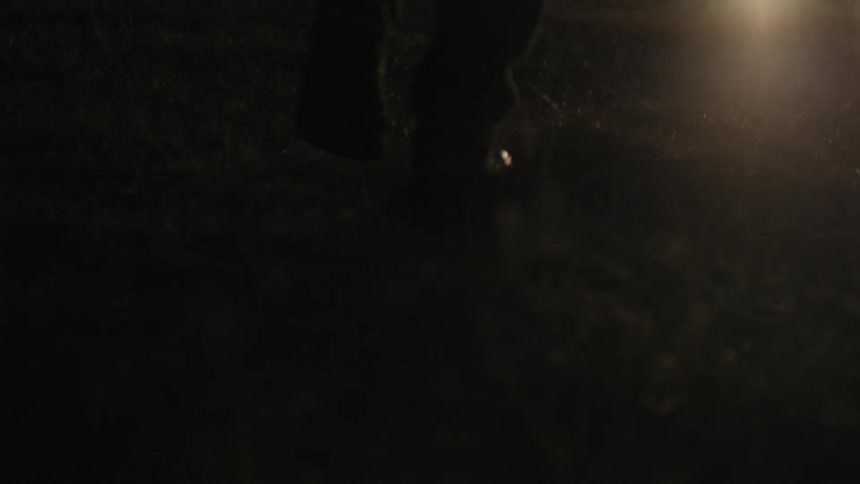 A person walks towards a vehicle with the headlights on
