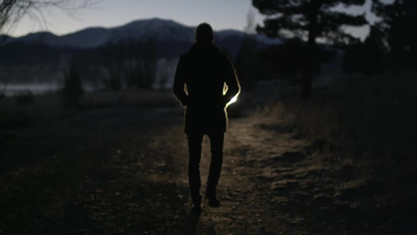Man standing in the wilderness with light shining behind him