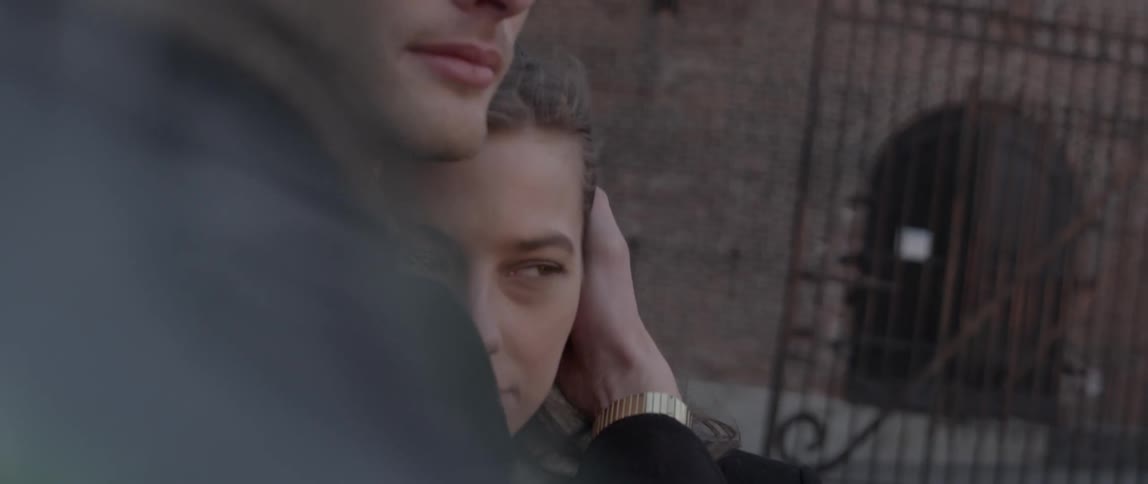 A young couple embracing outdoors in front of an old brick building