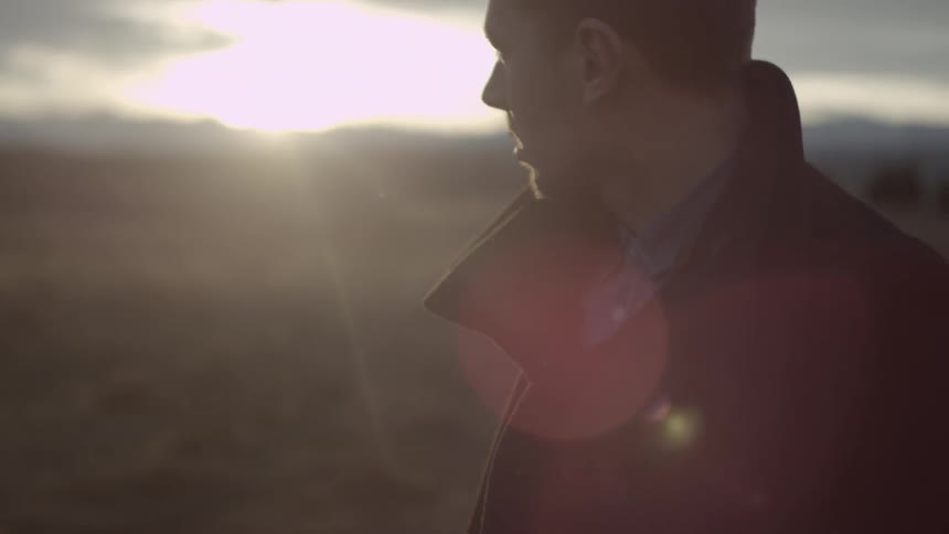 Man walking across the field looking towards the sunset