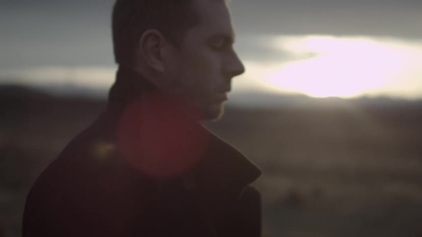 A man walks while the sun sets in the background