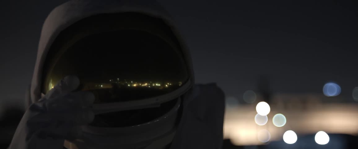 A man lowers the gold visor on the helmet of his astronaut suit