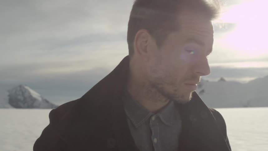 Man looking back towards the sun on a snowy plain
