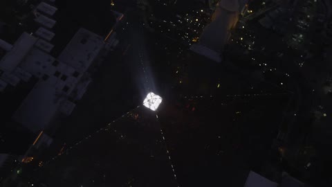 Top down view of a pyramid shaped glass building lit up at night
