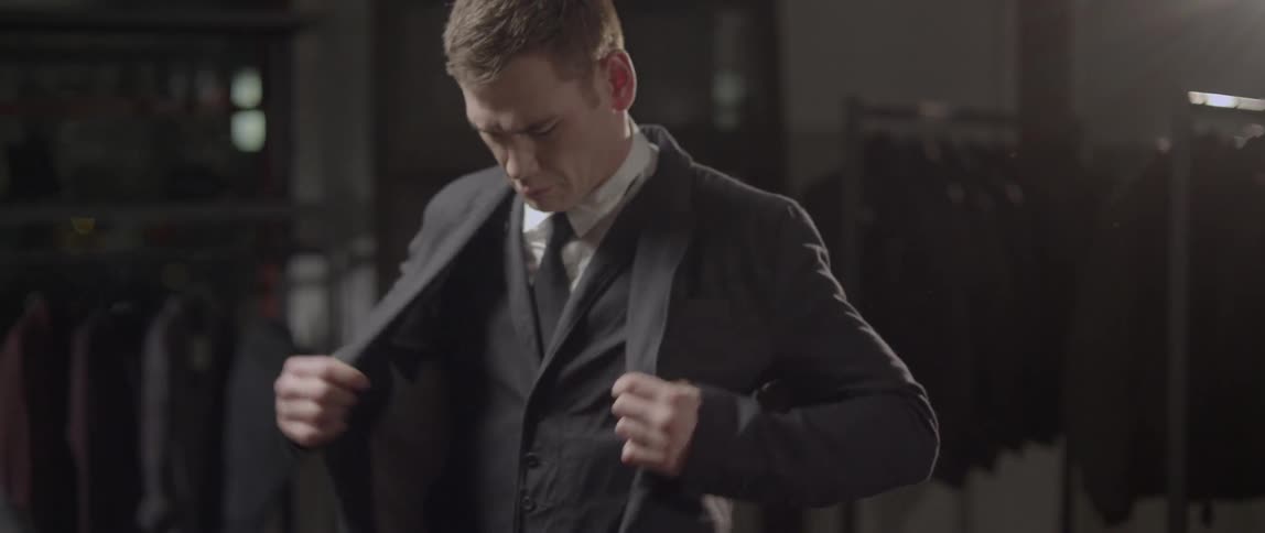 A man puts on a suit jacket