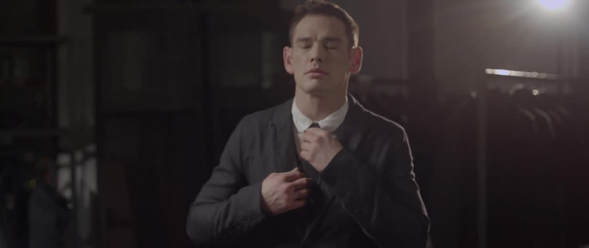 A man adjusts his suit and tie