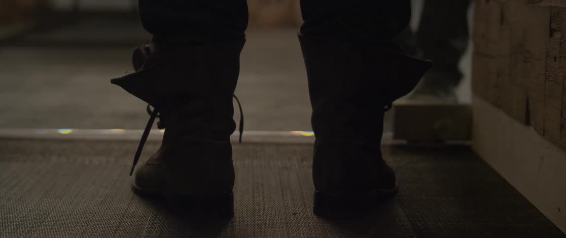 A person wearing boots stands at a glass door while waiting for someone to open it, then enters