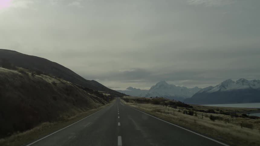 A road near a snow capped mountain on an overcast day