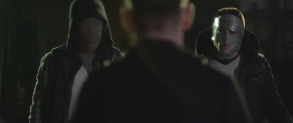 A man is confronted outside at night by two men wearing duct tape and stockings over their faces
