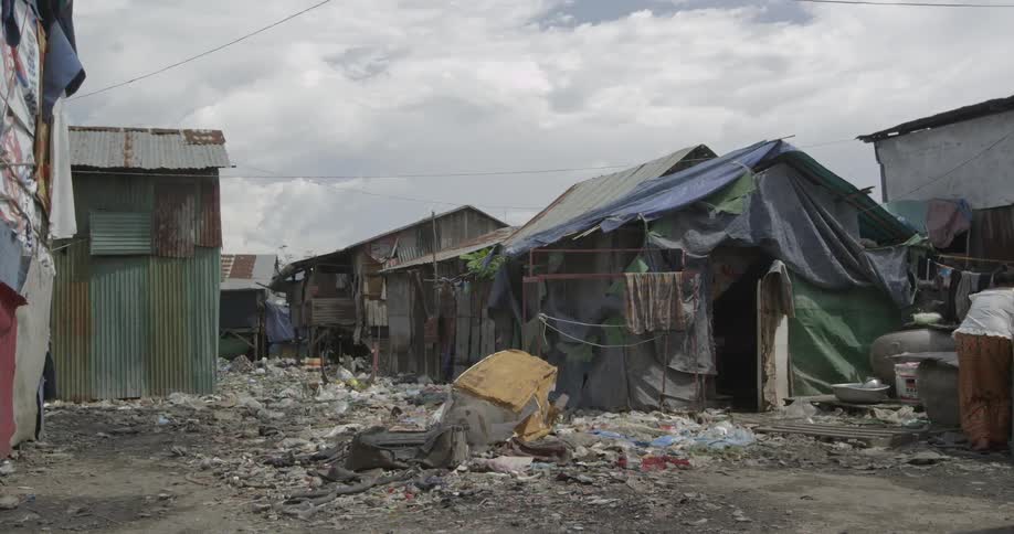 A junk pile in front of shanties on a cloudy day