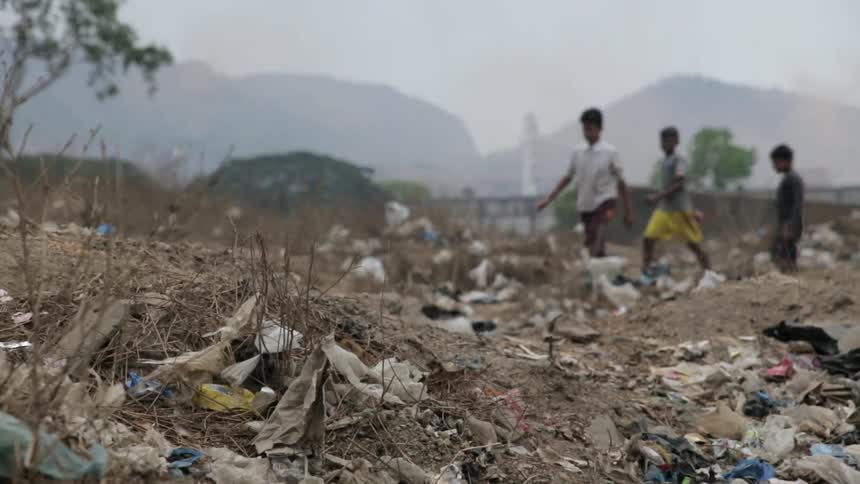 Kids walk through a dusty landfill