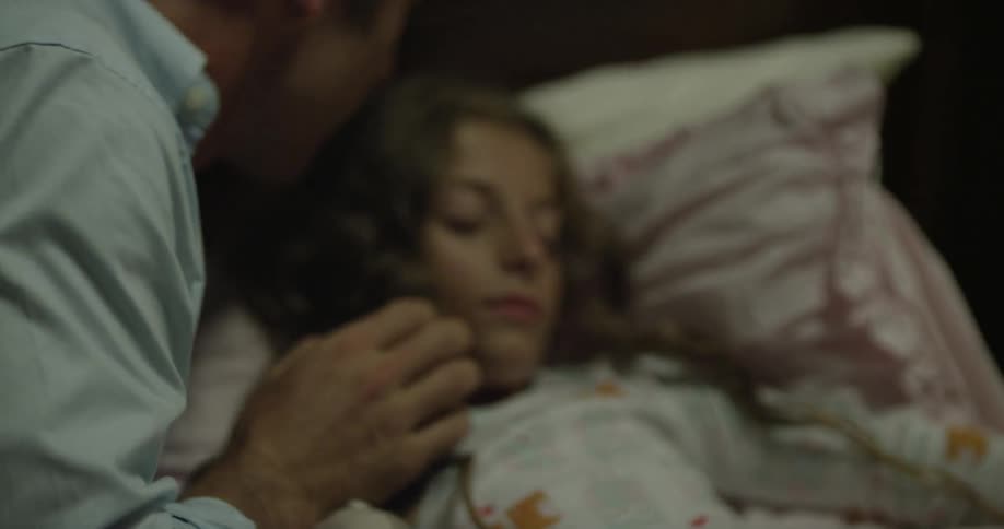Father kisses her daughter who has fallen asleep