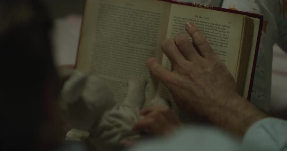 A young kid holding a stuffed bunny reading a book