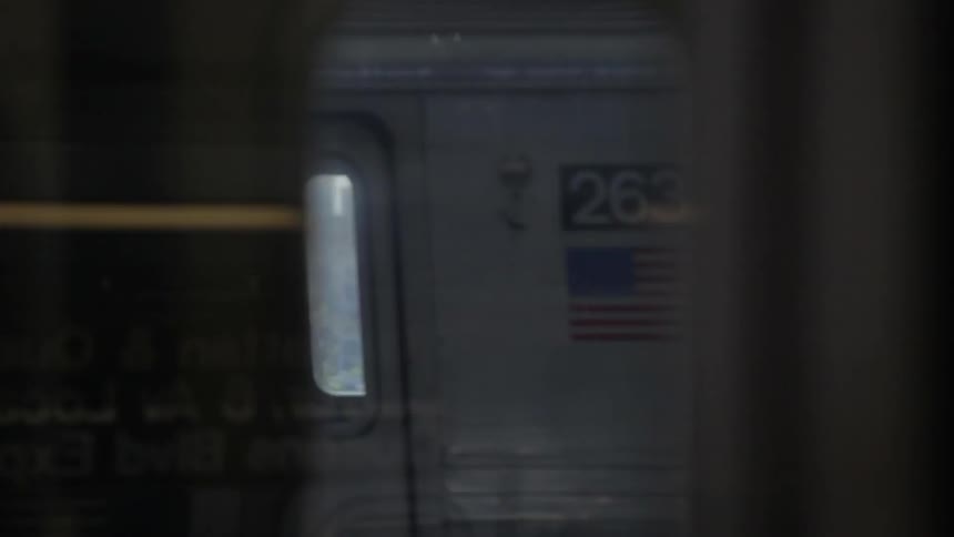 Two trains run parallel each other followed by the sight of city buildings
