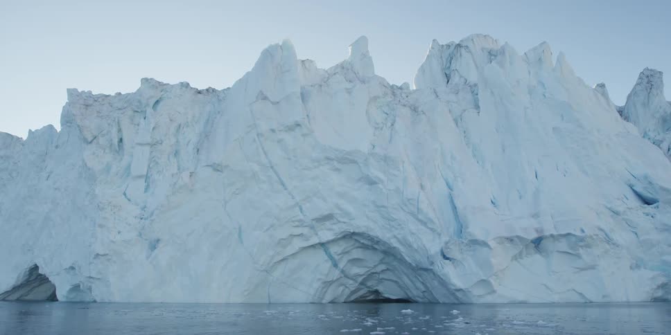 Large ice cliff with slow moving water in front during the day