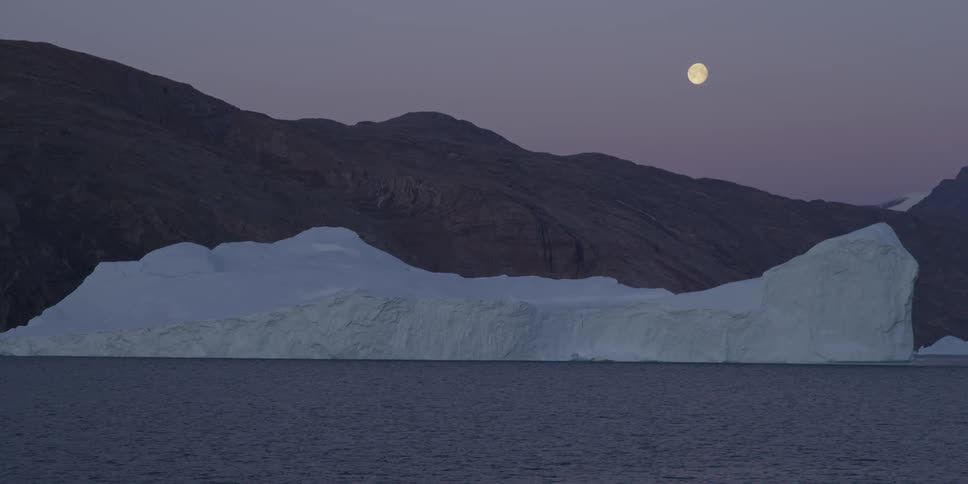 A giant glacier seen in the foreground while the moon is in the background