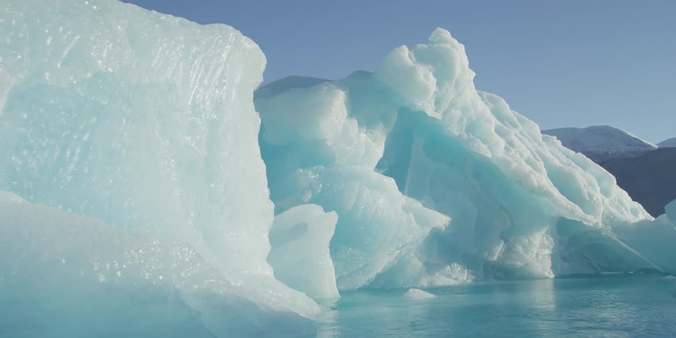 Blue glaciers sit with brilliant blue water at their base