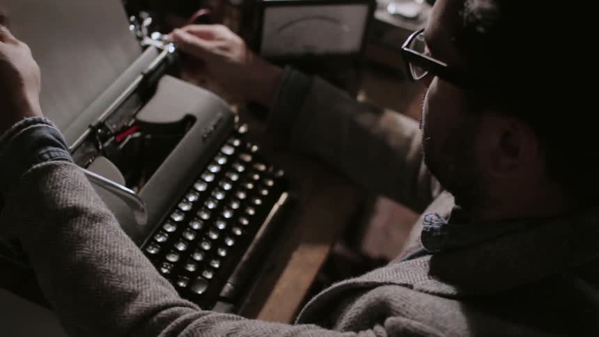 Man loads a piece of paper into a typewriter