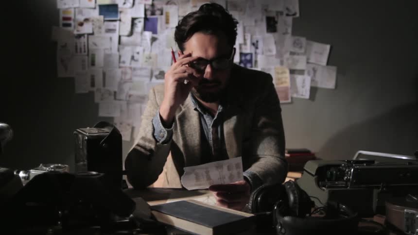 Man reads something while standing over his desk