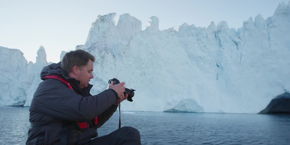 A man photographs glaciers from a boat