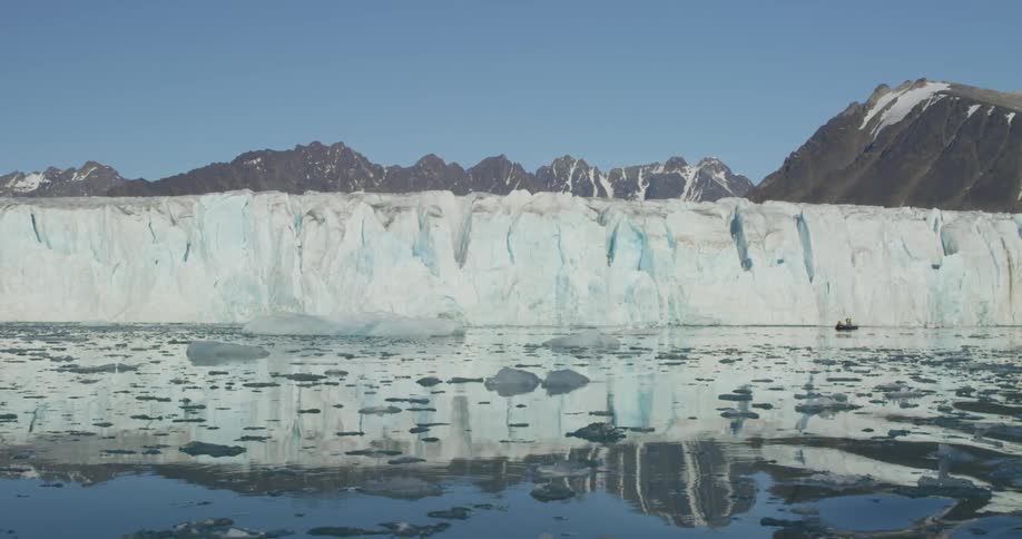 An inflatable boat moves near a glacier