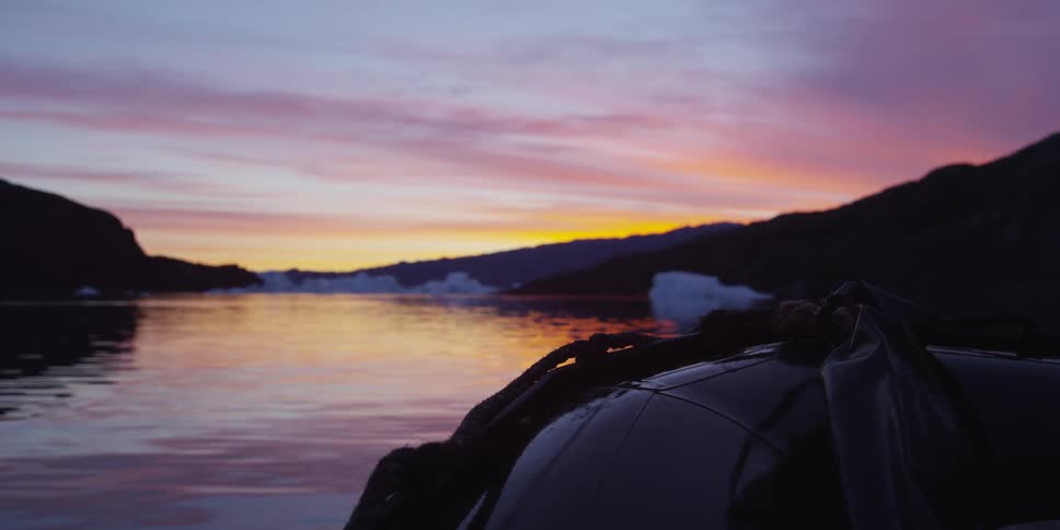 Raft going down the water at sunset