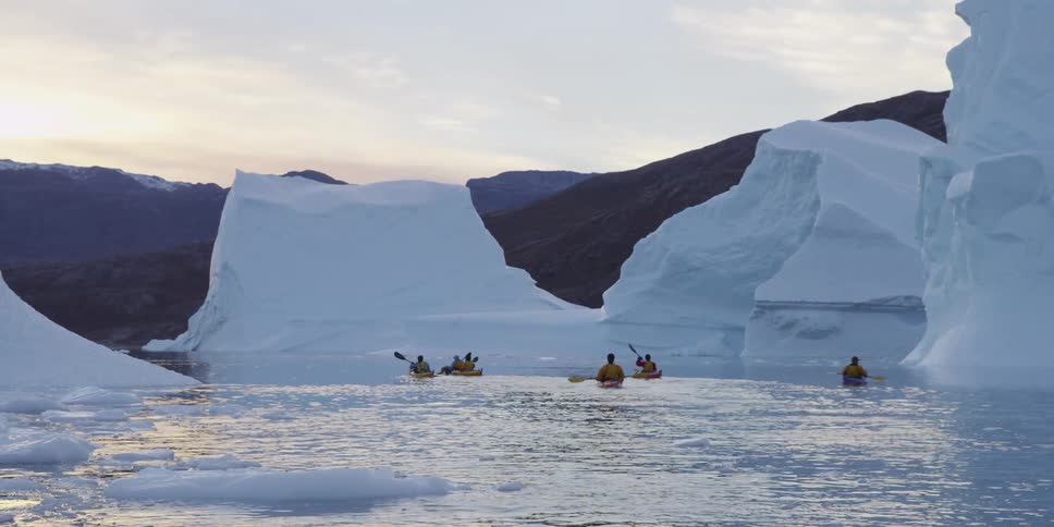 Kayakers paddle through icebergs