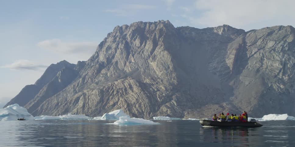 Several people on a boat in front of mountains