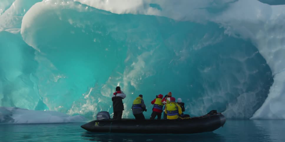 People in a raft drifting by a glacier