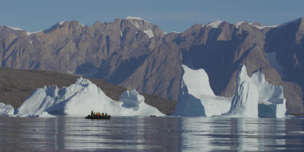 A boat full of people float near a glacier