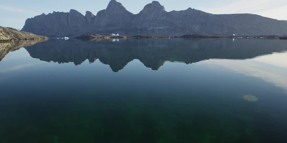A calm lake reflects the mountain behind it